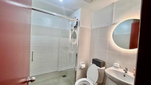 Un baño con inodoro, lavabo y espejo. en Dagaya Suites, en Bacolod