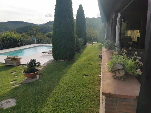 Il Casale del Conte في Fratta Todina: ساحة بها حمام سباحة وأشجار بجوار منزل