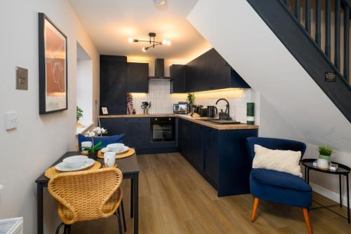 a kitchen with blue cabinets and a table and chairs at CityPad2 Stylish City Centre 2BR Apartment with Free Parking & WIFI in Cardiff