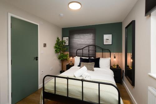 a bedroom with green walls and a bed with white sheets at CityPad2 Stylish City Centre 2BR Apartment with Free Parking & WIFI in Cardiff