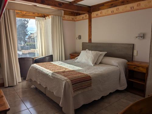a bedroom with a bed and a large window at Apart Hotel Bungalows Matute in San Carlos de Bariloche
