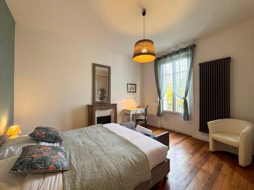 Le Cerf - Rambouillet city center في رامبوييه: غرفة نوم بها سرير وكرسي ونافذة