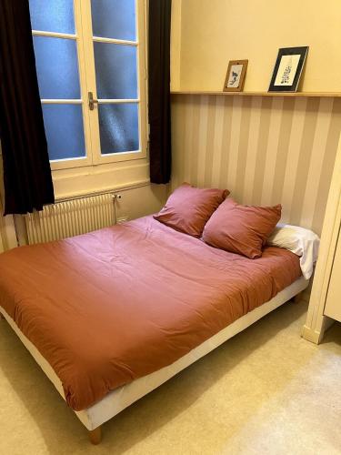 Le charme du Puy dans une ancienne verrerie في لو بوي: سرير به وسادتان في غرفة النوم