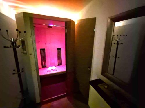 Un pasillo con un espejo y una habitación con luces rosas. en Schiestl, en Ramsau im Zillertal