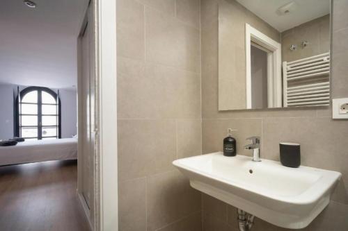 ein Badezimmer mit einem weißen Waschbecken und einem Spiegel in der Unterkunft AVG Numa Guilhou 4 in Gijón