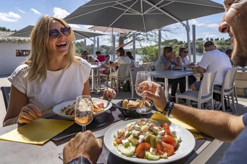 eine Frau, die mit einem Teller Essen an einem Tisch sitzt in der Unterkunft Camping 4 étoiles - Parc aquatique - ccbcafh in Jugon Les Lacs