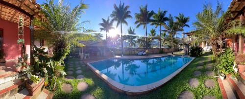 ein Swimmingpool vor einem Haus mit Palmen in der Unterkunft Sana Vale do Luar in Macaé