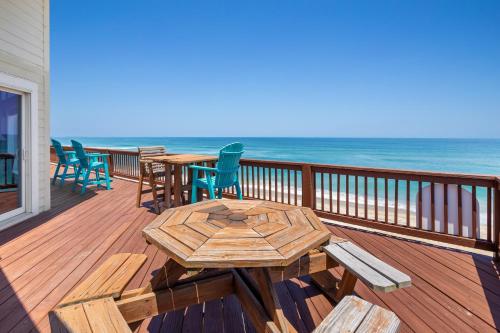 eine Holzterrasse mit Tischen und Stühlen am Strand in der Unterkunft 8045 - Mirlo Hi in Rodanthe