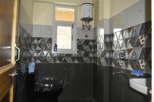 um banheiro com uma pia, um vaso sanitário e uma janela em Ghar Homestay em Kulu