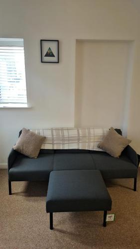 a couch sitting in a living room next to a window at Cockermouth Cottage - Lakes - Parking in Cockermouth