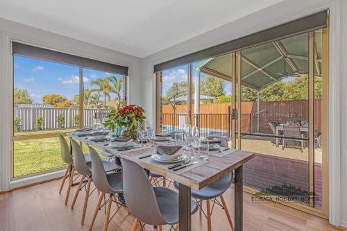 a dining room with a table and chairs and windows at Central Echuca Escape, Heated Pool, 3 BDR in Echuca
