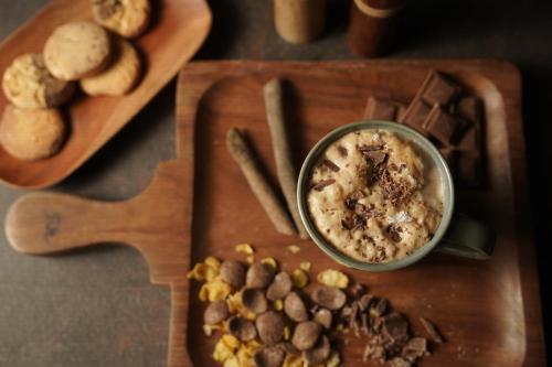 Una tabla de cortar de madera con un tazón de salsa y algo de comida. en Wonder Woods Boutique Hotel, en Darjeeling