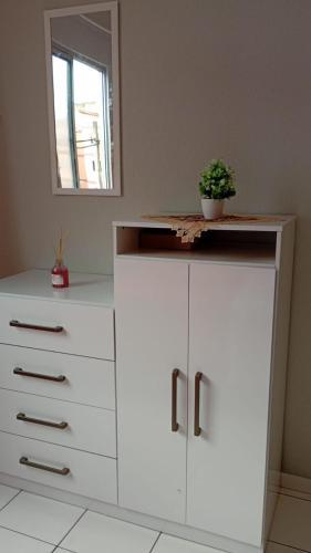 a white dresser with a potted plant on top of it at Apartamento aconchegante in Ananindeua