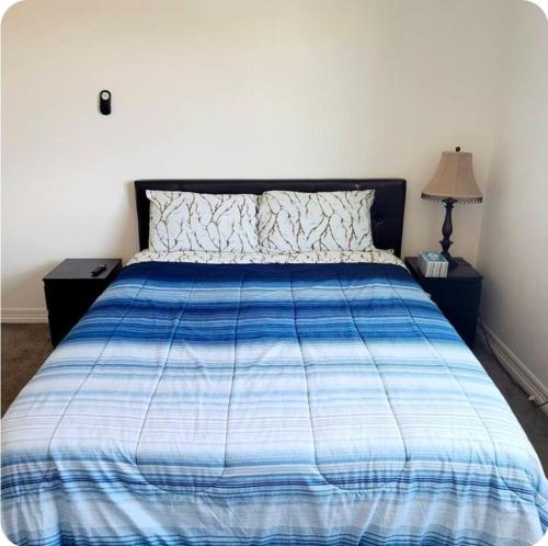 a bed with a blue and white comforter in a bedroom at Sweet stay near Denver airport in DEN