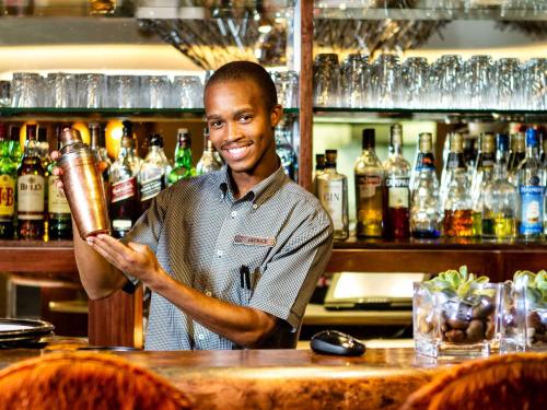 a man standing at a bar holding a drink at Kimberley Anne Hotel in Kimberley
