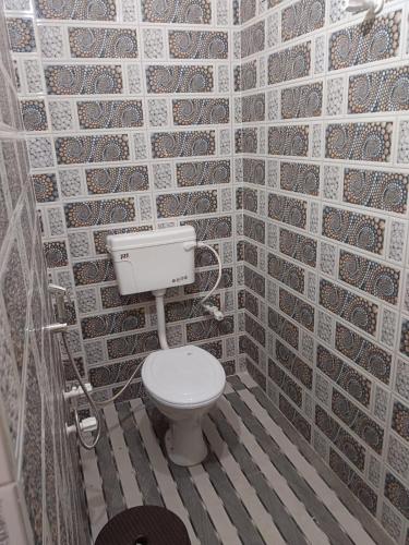 a bathroom with a toilet and a brick wall at Naimisharanya Atithi Bhavan in Naimishāranya