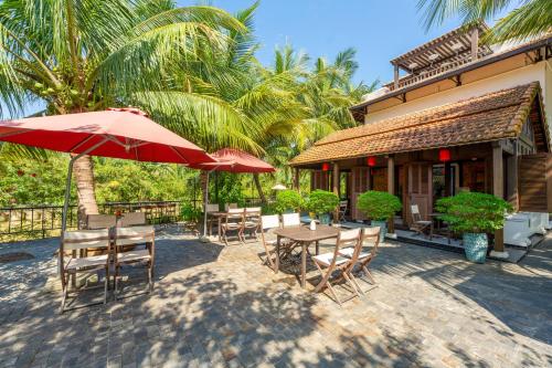 taras ze stołem, krzesłami i parasolem w obiekcie Mayci Eco Boutique Hotel Hoi An w Hoi An