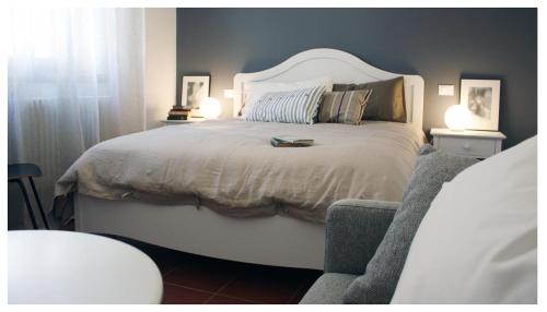 a bedroom with a large white bed with two lamps at A Cjase di Lise in Gemona del Friuli