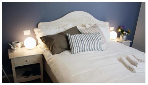 a white bed with two lamps on a night stand at A Cjase di Lise in Gemona del Friuli