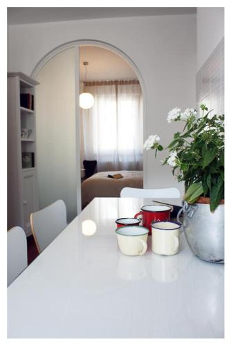 a white table with three bowls and a potted plant at A Cjase di Lise in Gemona del Friuli