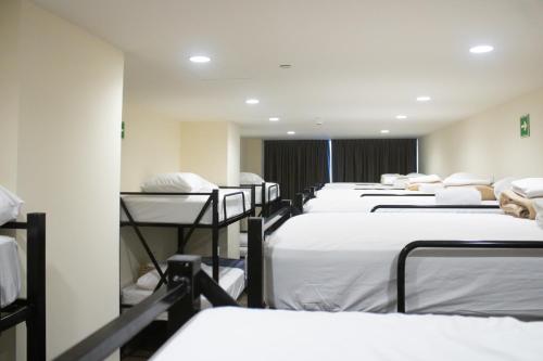 a row of beds in a room with white sheets at Travohostal Monterrey Historico in Monterrey