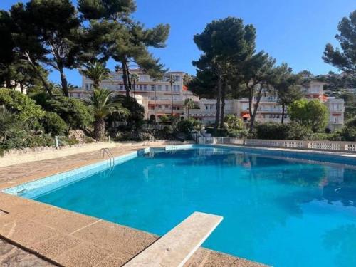 ein großer blauer Swimmingpool mit Bäumen und einem Gebäude in der Unterkunft Beautiful apartment in Mont des Oiseaux in Hyères