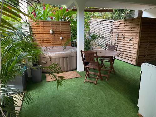 Un patio con una mesa y una bañera. en Ti bambou nature, en Sainte-Anne
