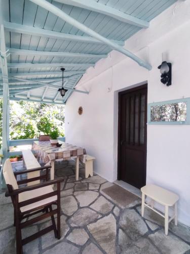a patio with a table and chairs and a blue ceiling at Our Summer Nest in Panormos Skopelos
