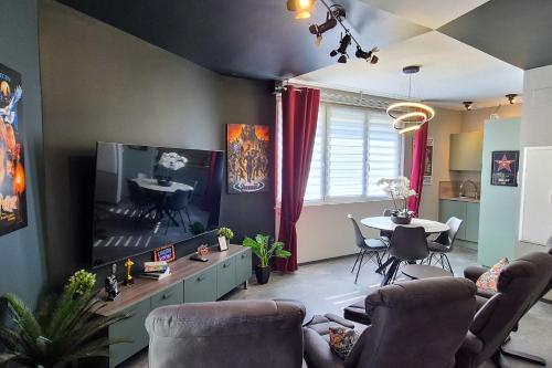 een woonkamer met een grote tv en een tafel bij Studio 68 Proche Basel Home Cinéma & Confort in Saint-Louis