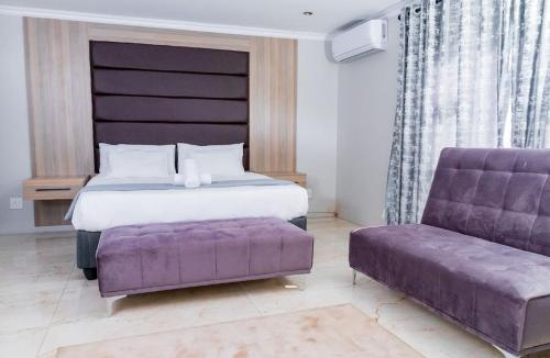 ein Schlafzimmer mit einem Bett und einer lila Couch in der Unterkunft Tindlovu GuestT House in Nelspruit