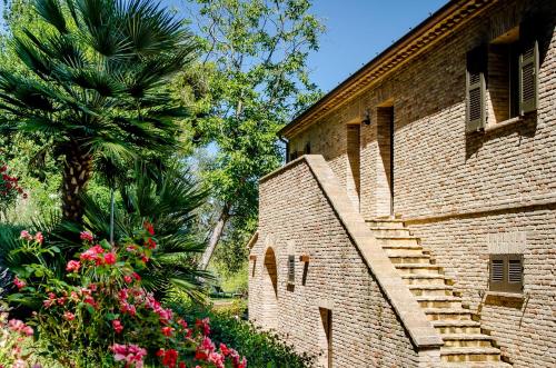 a brick building with a staircase next to a palm tree at CasaVostra - Ambience Suites in Ostra Vetere