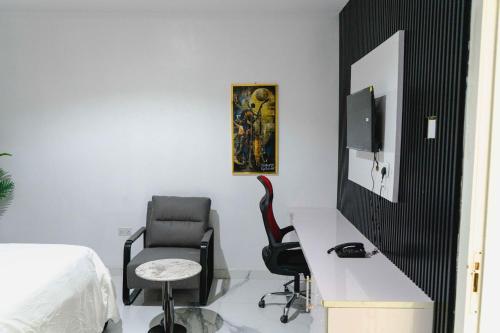 a bedroom with a desk and a chair and a tv at Olabanji Royal Garden Hotel in Ibadan