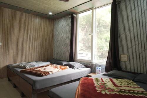 a bedroom with two twin beds and a window at Hotel Chauhan Palace in Uttarkāshi