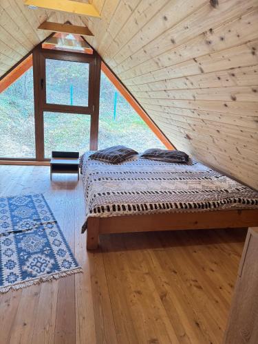 a bed in a wooden room with a window at Cabana Izvorul Rece Maramureş in Baia-Sprie