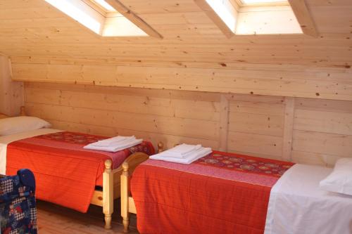 two beds in a room with wooden walls and windows at Albergo Diffuso Faller in Faller