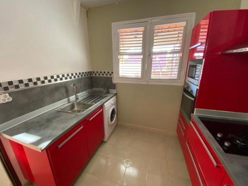 a red kitchen with a sink and a dishwasher at Maison de vacance 2 Chambres à 200m de la plage in Sainte-Anne