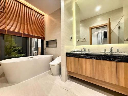 a bathroom with a tub and a toilet and a sink at Chalong Brand New 4BR Pool Villa Phuket VVPHU51 in Chalong 
