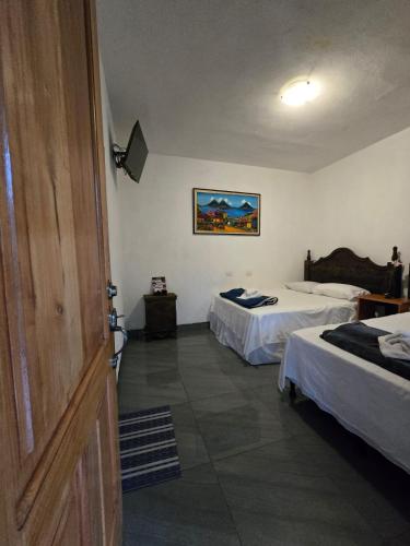 a hotel room with two beds and a door at Valle de Toliman in San Lucas Tolimán