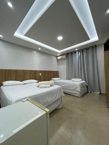 two beds in a room with a large ceiling at Maxi Palace hotel in Capitão Leônidas Marques