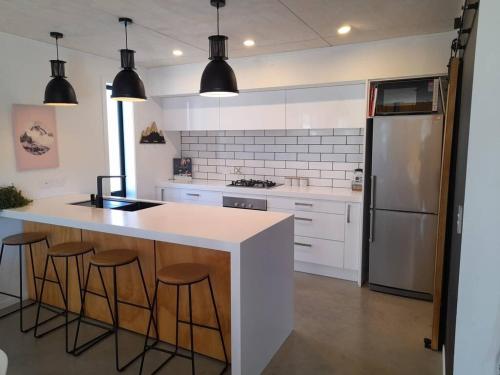 a kitchen with a counter with stools and a refrigerator at Beautiful Home in Lake Hawea in Lake Hawea