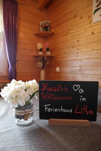 a sign on a table with flowers in a room at Ferienhaus LiRa in Drobollach am Faaker See