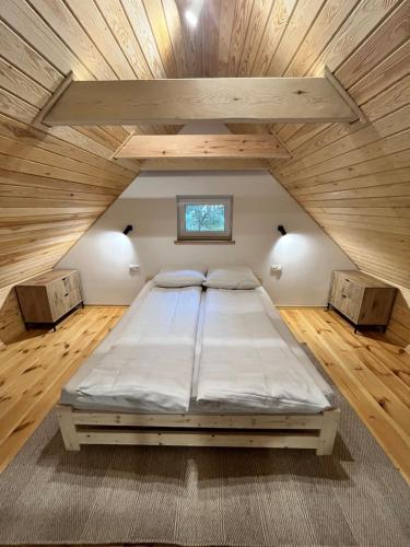 a large bed in a room with a wooden ceiling at Whispering Woods Cabin in Milicz