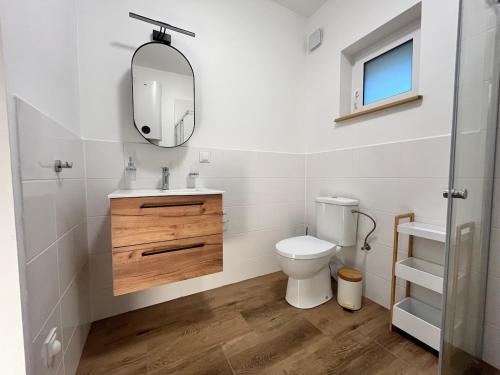 een witte badkamer met een toilet en een spiegel bij Whispering Woods Cabin in Milicz