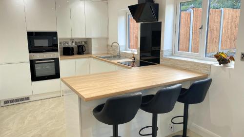a kitchen with a wooden counter and two blue bar stools at Ready Stay Work Lodge in Birmingham