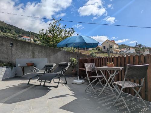 un patio con sedie, un tavolo e un ombrellone di Monte Gordo Accommodation a Ribeira Brava