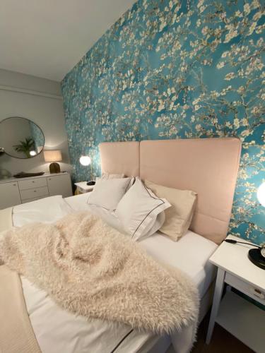a bedroom with a white bed with a floral wall at Bonne Vie Cottage - Zebegény in Zebegény