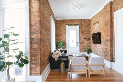 a brick wall in a living room with a table and chairs at East Main Your Merry Modern Downtown Getaway in Bowling Green