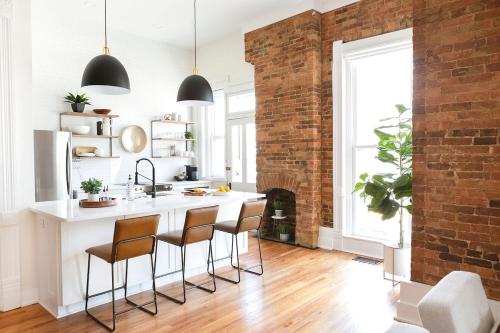 a kitchen with a brick wall and a kitchen island with chairs at East Main Your Merry Modern Downtown Getaway in Bowling Green