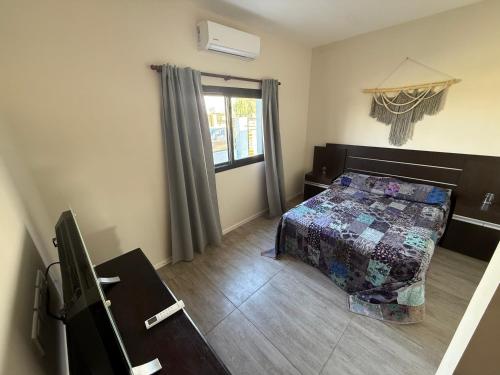 a bedroom with a bed and a desk and a window at Abril, alquiler temporario in Piñero