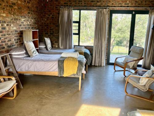 a bedroom with two beds and a brick wall at De Krantz 6 Estate in Clarens